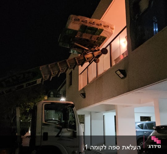 מנוף מרים חפצים לקומה עליונה של בניין בלילה